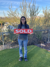 photo of a smiling home buyer standing outside in front of a sold sign.